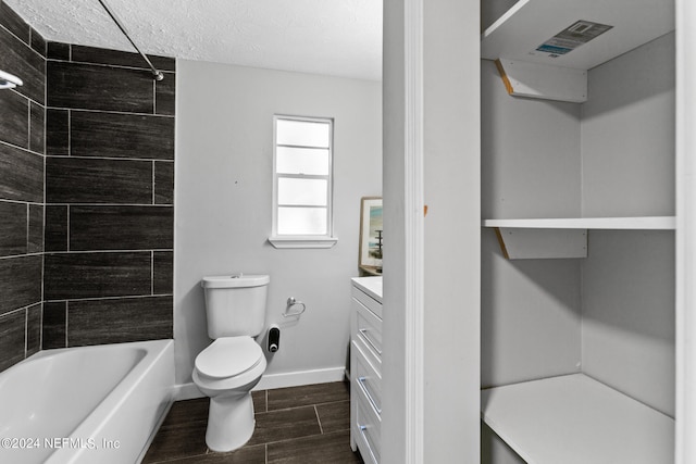 full bathroom with vanity, toilet, a textured ceiling, and tiled shower / bath