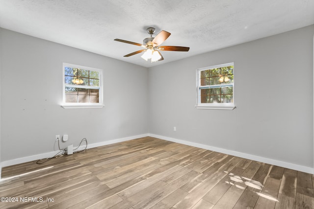 unfurnished room with a wealth of natural light, a textured ceiling, wood-type flooring, and ceiling fan