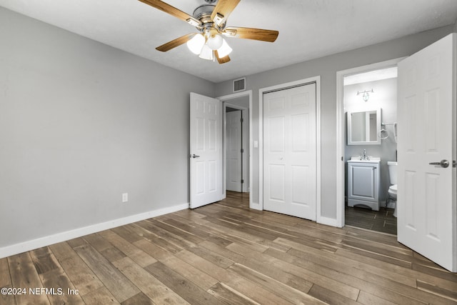 unfurnished bedroom featuring connected bathroom, hardwood / wood-style floors, sink, and ceiling fan