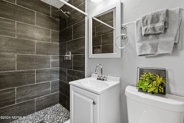 bathroom featuring vanity, toilet, and a tile shower