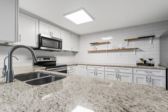 kitchen featuring white cabinets, light stone countertops, stainless steel appliances, and backsplash