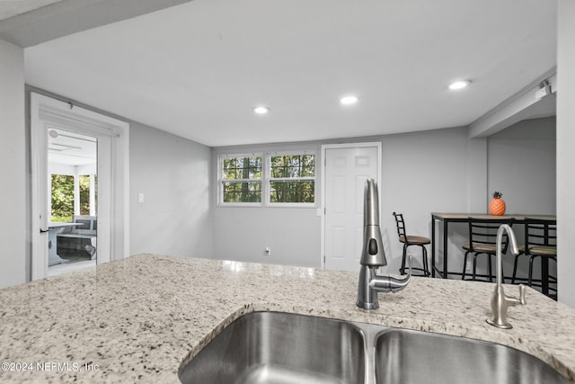 kitchen with light stone countertops, sink, and plenty of natural light