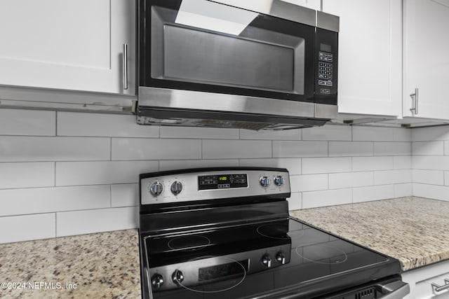 kitchen featuring backsplash, appliances with stainless steel finishes, light stone counters, and white cabinets