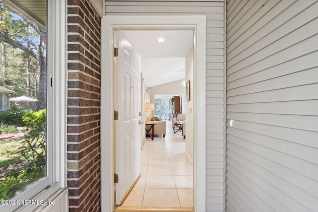 4508 Middleton Park Cir W, Jacksonville, FL 32224 - hallway featuring lofted ceiling, brick wall, and light tile patterned floors