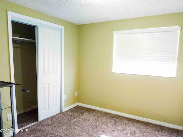 unfurnished bedroom with a textured ceiling, a closet, and carpet floors