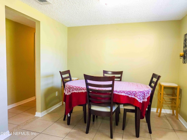 tiled dining room featuring a textured ceiling