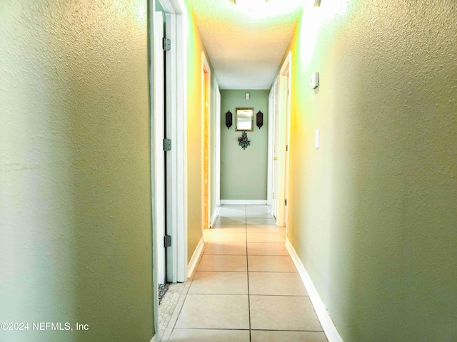 hallway with a textured ceiling and light tile patterned floors