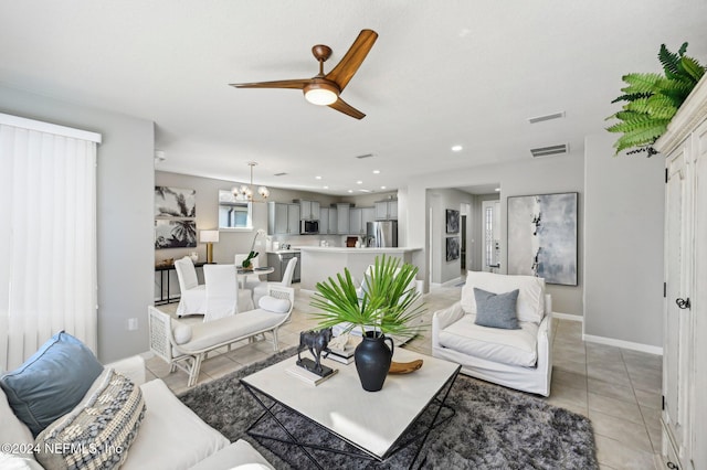 living room with light tile patterned floors and ceiling fan with notable chandelier