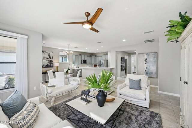 living room featuring ceiling fan with notable chandelier and light tile patterned floors