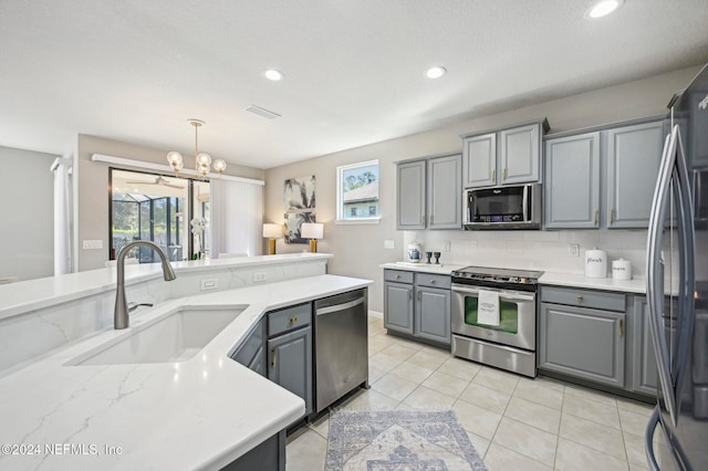 kitchen featuring appliances with stainless steel finishes, gray cabinetry, sink, decorative light fixtures, and a notable chandelier