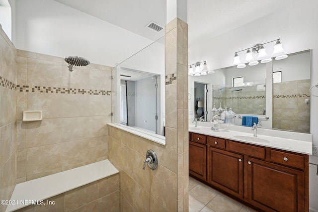 bathroom with tile patterned flooring, vanity, and tiled shower