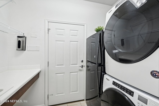 clothes washing area featuring light tile patterned floors and stacked washer / dryer