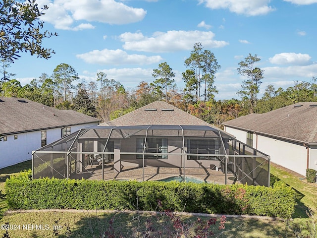 back of property with a patio, glass enclosure, and a swimming pool