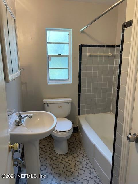 bathroom featuring tiled shower / bath, tile patterned floors, and toilet