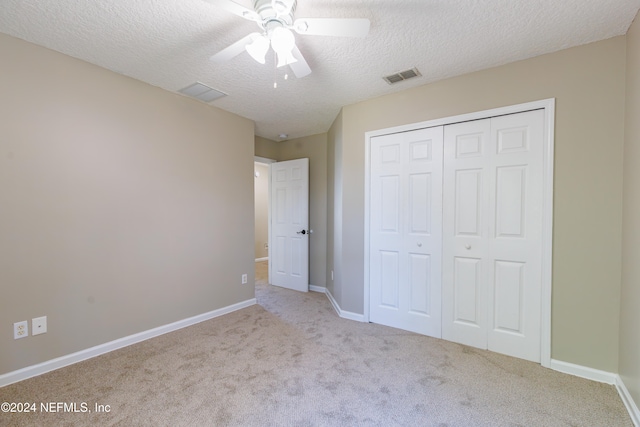 unfurnished bedroom with a closet, a textured ceiling, light colored carpet, and ceiling fan