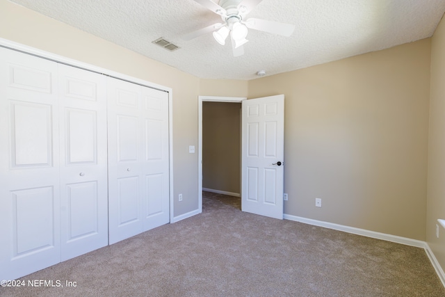 unfurnished bedroom with a closet, a textured ceiling, light colored carpet, and ceiling fan