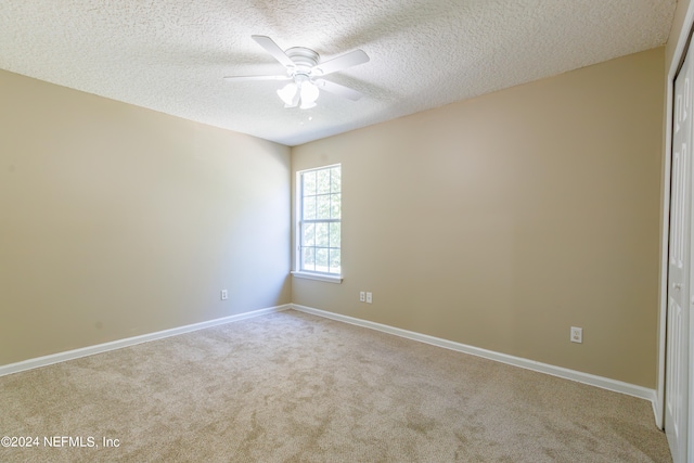 empty room with a textured ceiling, light colored carpet, and ceiling fan