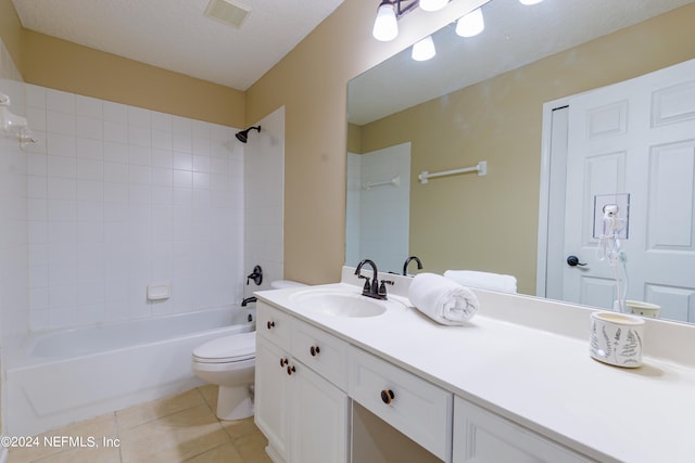 full bathroom with a textured ceiling, toilet, vanity, tiled shower / bath combo, and tile patterned flooring