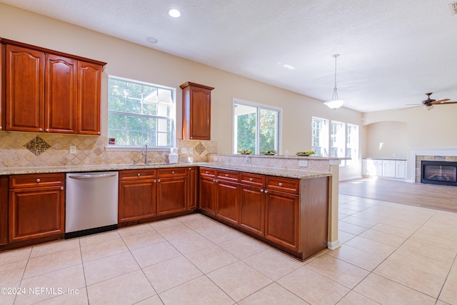 kitchen with ceiling fan, light stone countertops, stainless steel dishwasher, a fireplace, and decorative light fixtures