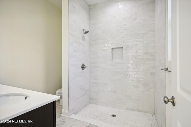 bathroom with vanity, tiled shower, and toilet