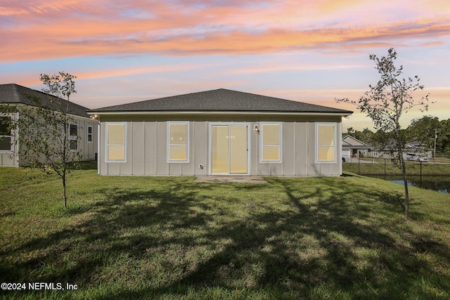 back house at dusk with a lawn