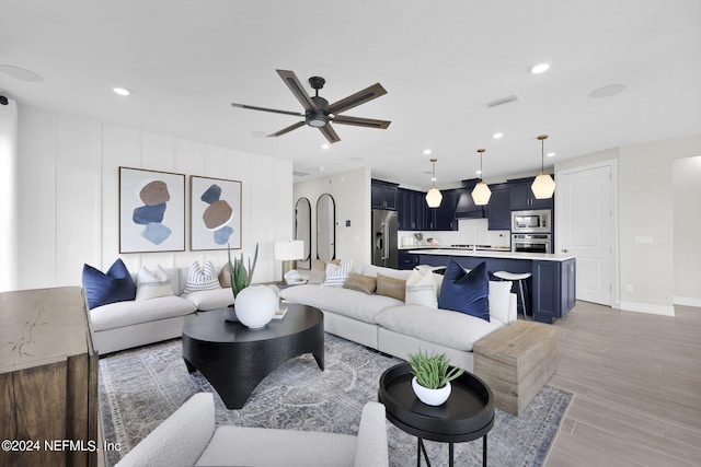 living room with ceiling fan, sink, and light hardwood / wood-style floors