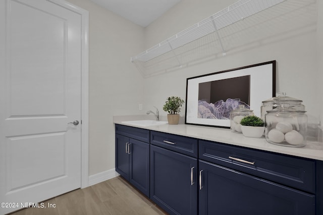 bar featuring blue cabinetry, light hardwood / wood-style floors, and sink