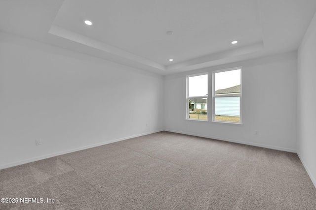 spare room with recessed lighting, baseboards, a tray ceiling, and carpet floors