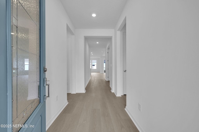 hallway featuring recessed lighting, baseboards, and light wood-type flooring