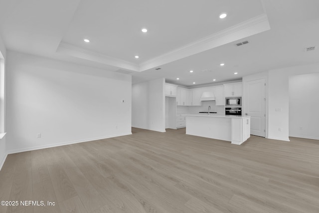 unfurnished living room featuring light wood finished floors, visible vents, crown molding, recessed lighting, and a raised ceiling