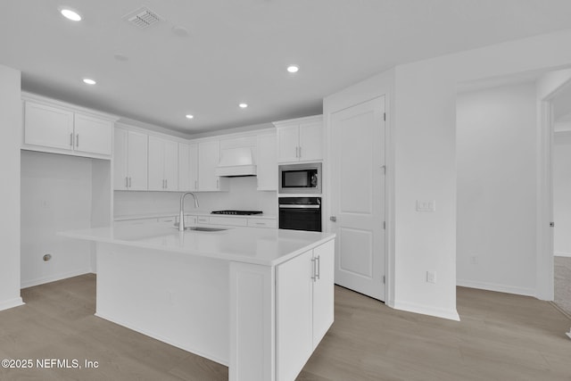 kitchen featuring visible vents, black appliances, custom range hood, a sink, and white cabinetry