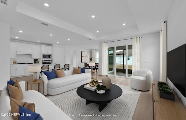 living area featuring visible vents, light wood finished floors, recessed lighting, ornamental molding, and a raised ceiling