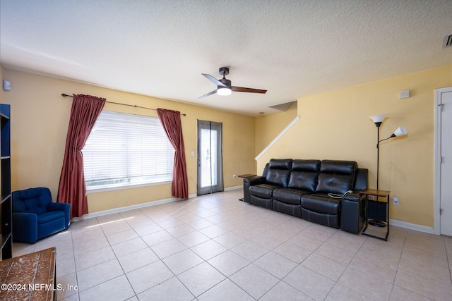 living room with ceiling fan, a textured ceiling, and light tile patterned floors