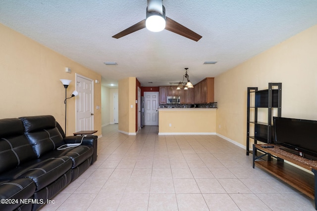 tiled living room with a textured ceiling and ceiling fan with notable chandelier