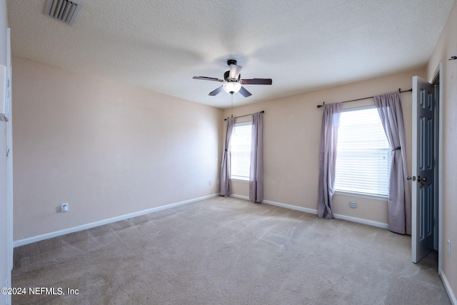 carpeted spare room featuring a wealth of natural light, a textured ceiling, and ceiling fan