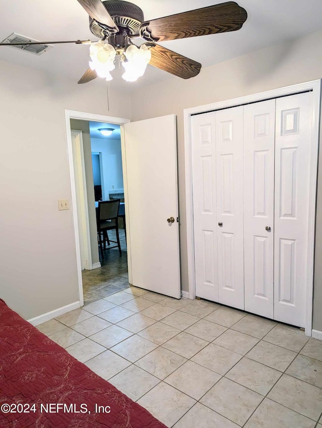 unfurnished bedroom featuring ceiling fan, light tile patterned flooring, and a closet