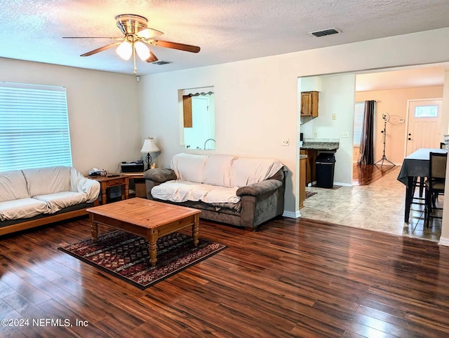 living room featuring ceiling fan, hardwood / wood-style floors, and a textured ceiling