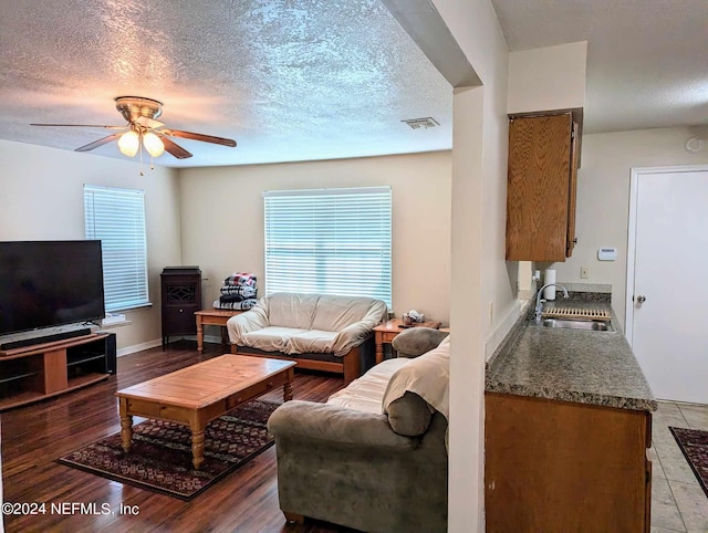 living room with hardwood / wood-style floors, ceiling fan, sink, and a textured ceiling