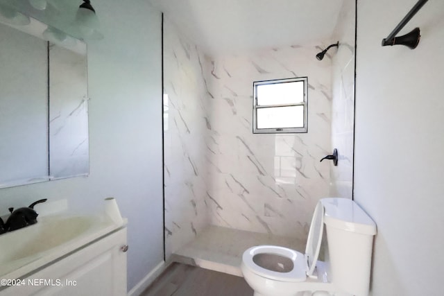 bathroom featuring toilet, tiled shower, and vanity