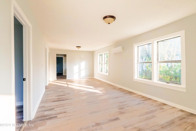 empty room featuring a wall unit AC and light wood-type flooring