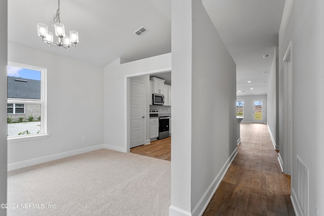 corridor with an inviting chandelier and light hardwood / wood-style floors