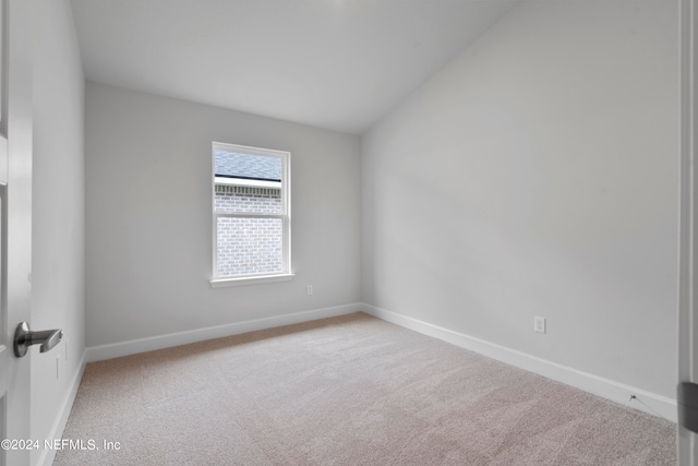 carpeted empty room with lofted ceiling