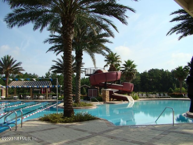 view of swimming pool with a water slide and a patio area