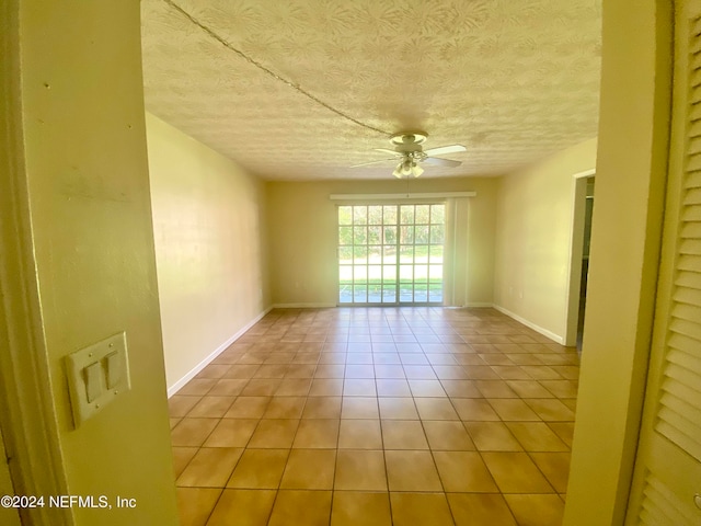 tiled empty room featuring a textured ceiling and ceiling fan