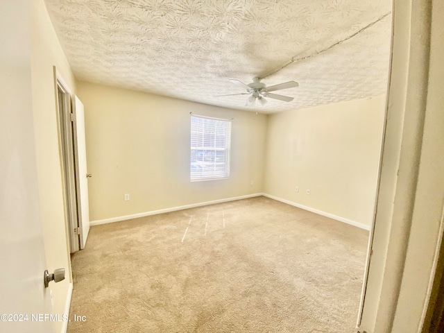 empty room featuring light carpet, a textured ceiling, and ceiling fan