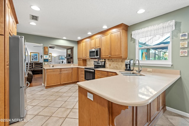 kitchen featuring sink, appliances with stainless steel finishes, kitchen peninsula, and backsplash