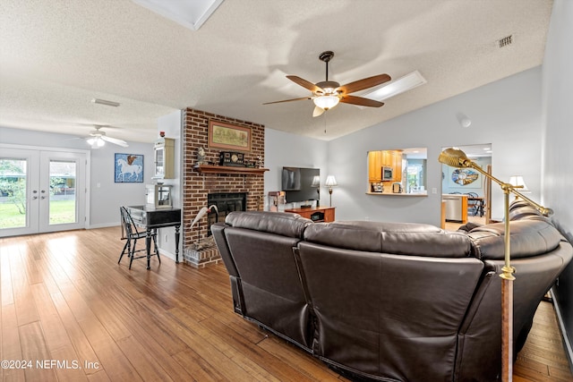 living room with a textured ceiling, hardwood / wood-style flooring, a fireplace, and vaulted ceiling