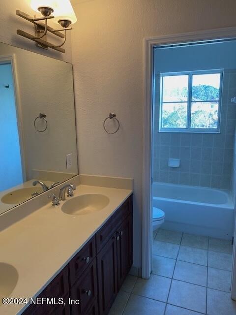 full bathroom featuring tiled shower / bath combo, vanity, tile patterned floors, and toilet