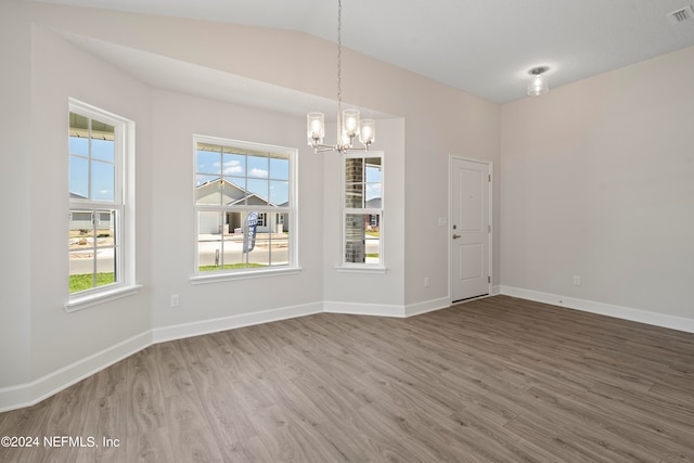 unfurnished dining area with a notable chandelier, vaulted ceiling, and wood-type flooring