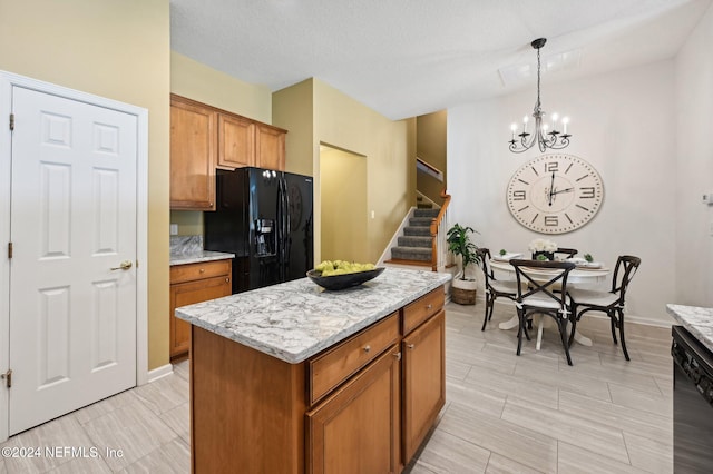 kitchen featuring a kitchen island, black appliances, light stone countertops, pendant lighting, and a textured ceiling